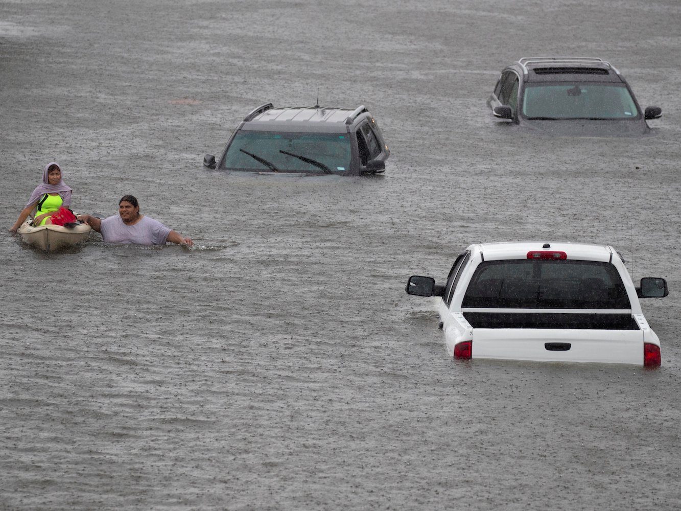 A resident of Houston  (right) rescues a stranded woman (left) from a flooded area.