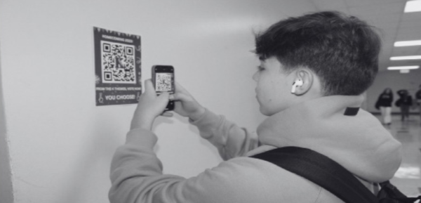 GET INVOLVED: Senior Daniel Entebi scans a QR code to vote for this year’s Homecoming theme.